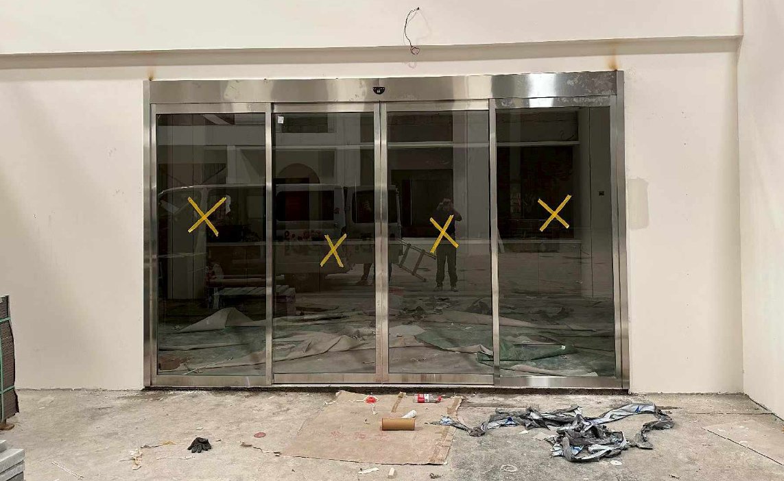 四扇玻璃感应门安装现场：两固定边扇两中间活动扇，玻璃贴叉形保护标记